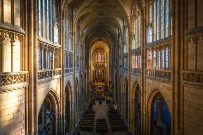 Interno della Cattedrale di San Vito a Praga con prospettiva sulla navata gotica e luce zenitale dalle vetrate.