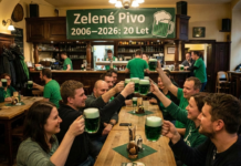 Zelené Pivo: vent’anni di liquido radioattivo. Perché i cechi lo bevono (e perché dovresti farlo anche tu) Un gruppo di persone allegre brinda sollevando grandi boccali di birra verde brillante in un pub tradizionale ceco affollato. Sullo sfondo, sopra il bancone in legno, è appeso uno striscione verde con la scritta bianca "Zelené Pivo 2006–2026: 20 Let" e un'icona grafica di un boccale di birra.